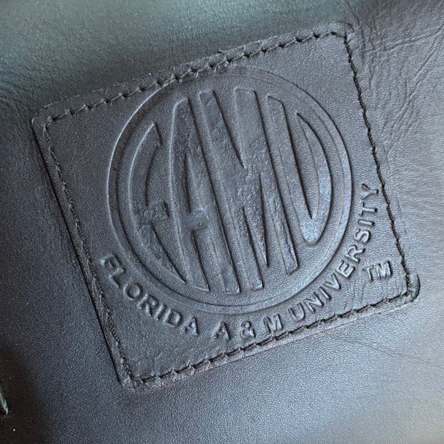 close up of embossed leather logo for FAMU Florida A&M University black barrel bag.