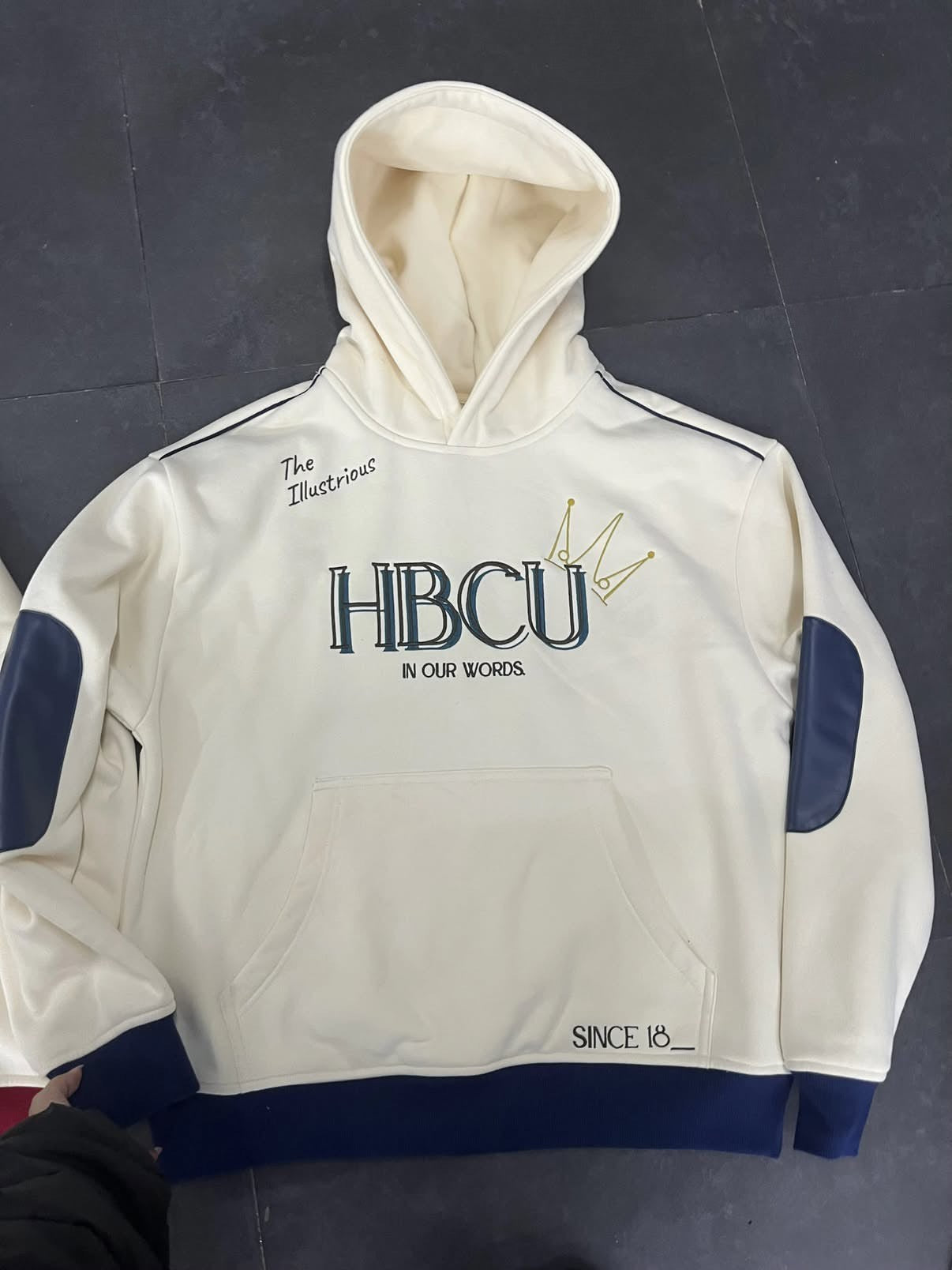 White hoodie with the word 'HBCU' on the front blue accents and text on a dark background