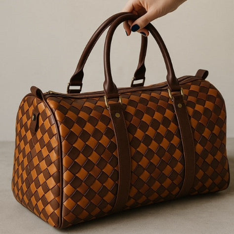Brown woven duffel bag held by a hand against a neutral background
