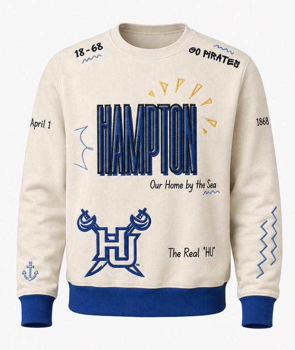 An off-white crewneck sweatshirt for Hampton University with royal blue ribbed cuffs and hem, featuring a navy and blue graphic print on the front with the text 'HAMPTON' and 'Our Home by the Sea'.