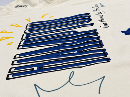 Angled close-up of blue Hampton lettering and Our Home by the Sea text on the cream sweatshirt.