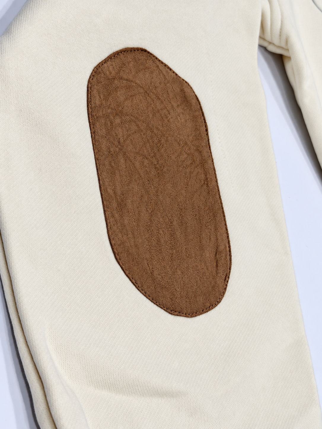 lose-up of the stitched brown suede oval elbow patch on the cream Hampton University sweatshirt.