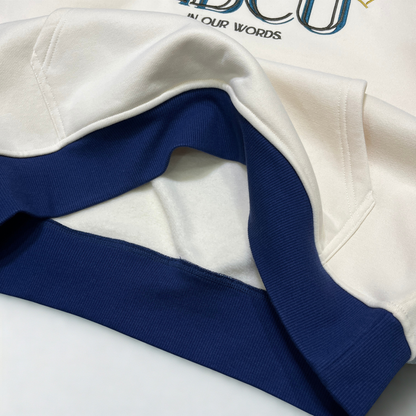 Close-up of a white sweatshirt with a contrasting dark blue ribbed collar and hem, featuring a partial view of a graphic print on the chest or the HBCU Legacy hoodie.