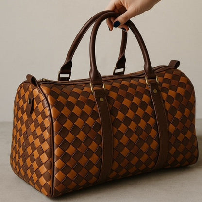 Brown woven duffel bag held by a hand against a neutral background